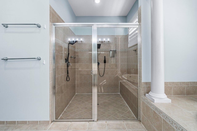 bathroom with decorative columns, tile patterned floors, and a shower with shower door