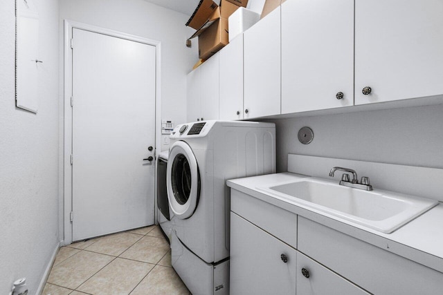 clothes washing area featuring cabinets, light tile patterned flooring, washer and clothes dryer, and sink