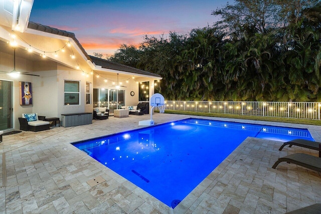 pool at dusk with outdoor lounge area and a patio