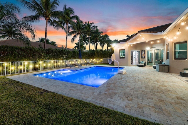 pool at dusk with a patio area