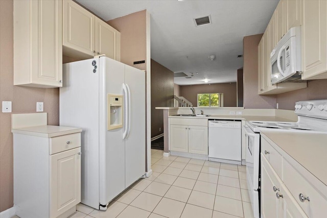 kitchen with kitchen peninsula, white appliances, sink, white cabinetry, and light tile patterned flooring