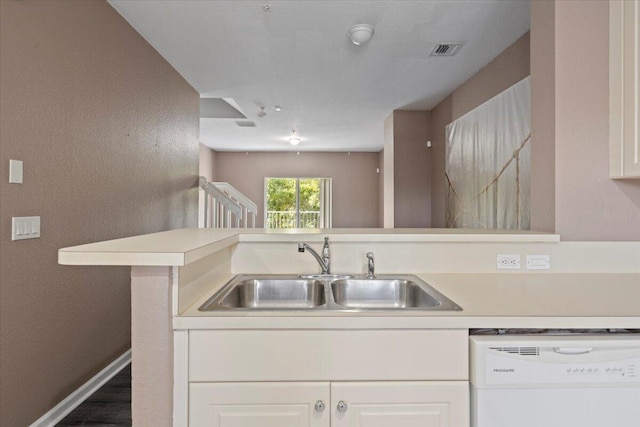 kitchen featuring kitchen peninsula, dishwasher, white cabinets, and sink