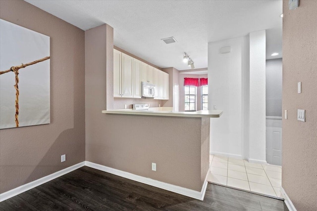 kitchen with kitchen peninsula, range, a textured ceiling, and light hardwood / wood-style flooring