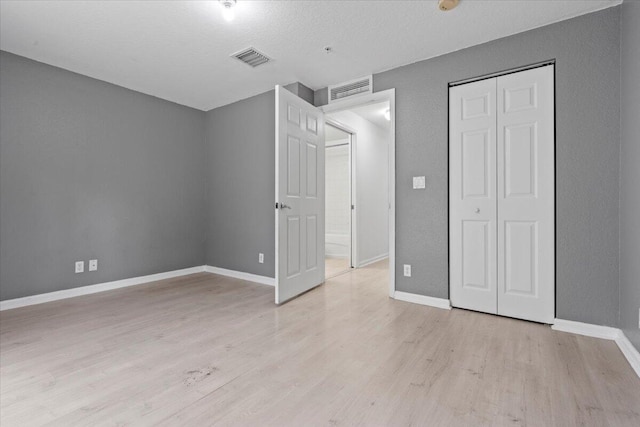 unfurnished bedroom with a closet, light hardwood / wood-style flooring, and a textured ceiling