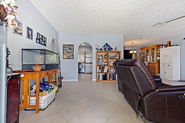 living room with light tile patterned floors, a notable chandelier, and a textured ceiling