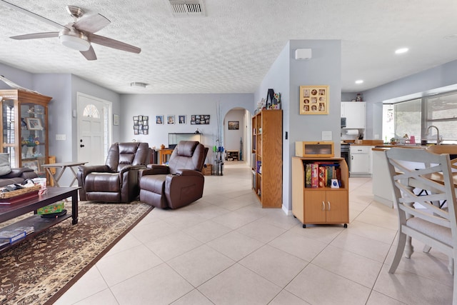 living room featuring ceiling fan, a textured ceiling, and light tile patterned flooring