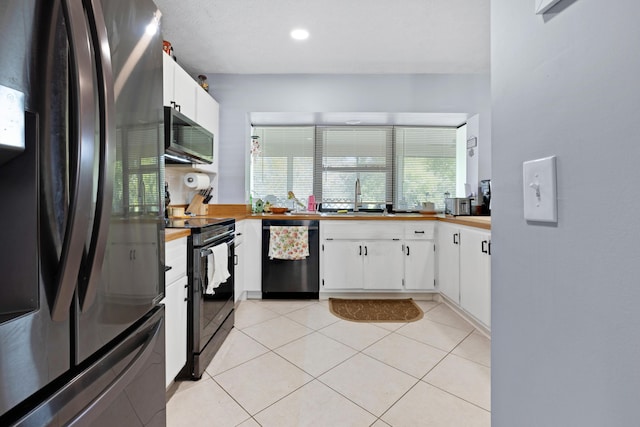 kitchen with light tile patterned flooring, sink, white cabinets, and black appliances