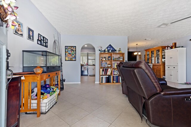 living room featuring light tile patterned floors, a textured ceiling, and a notable chandelier