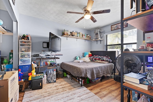 bedroom featuring ceiling fan, a textured ceiling, and light hardwood / wood-style floors