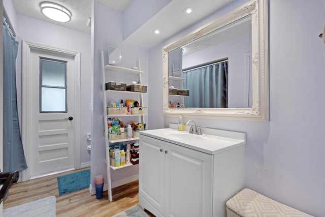 bathroom with hardwood / wood-style flooring, vanity, toilet, and a textured ceiling