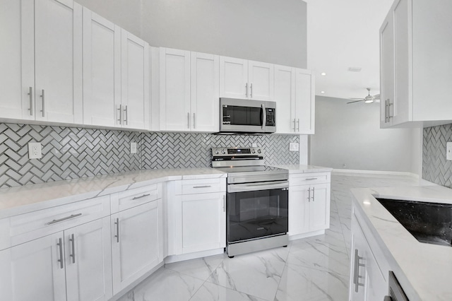 kitchen with white cabinets, light stone countertops, appliances with stainless steel finishes, and tasteful backsplash