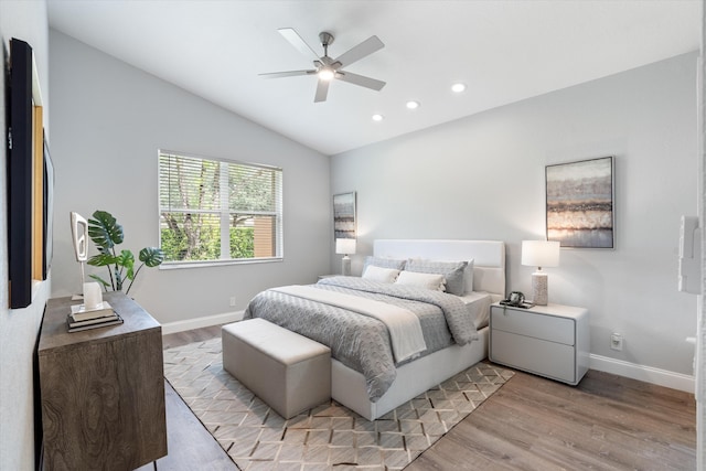 bedroom with ceiling fan, light hardwood / wood-style floors, and vaulted ceiling