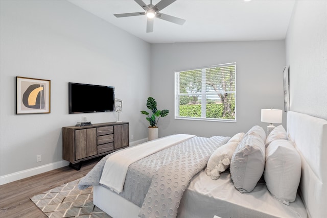 bedroom with ceiling fan, hardwood / wood-style floors, and vaulted ceiling