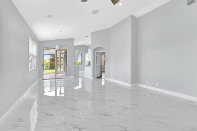 empty room with ceiling fan with notable chandelier and lofted ceiling