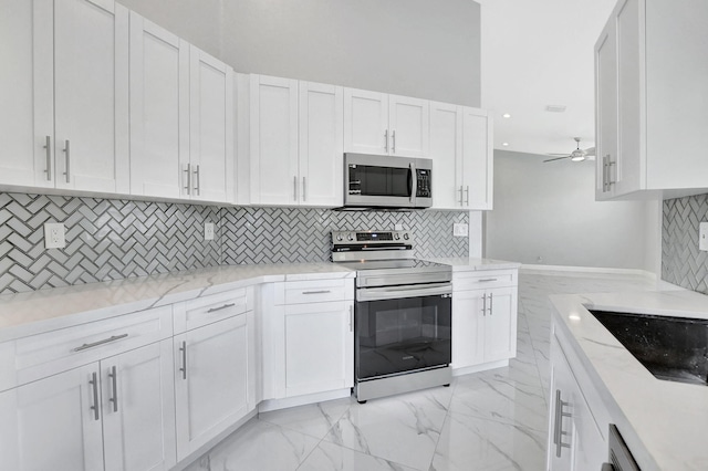 kitchen with decorative backsplash, stainless steel appliances, white cabinetry, and light stone counters