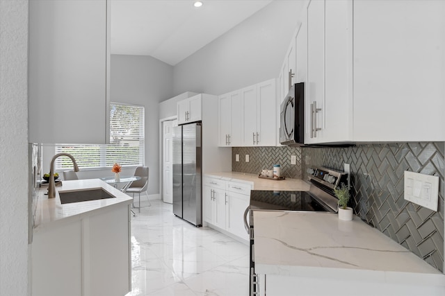 kitchen featuring appliances with stainless steel finishes, backsplash, light stone counters, sink, and white cabinets