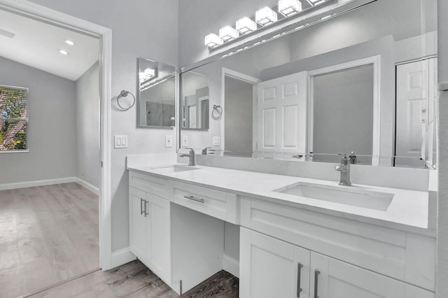 bathroom with hardwood / wood-style flooring, vanity, and vaulted ceiling