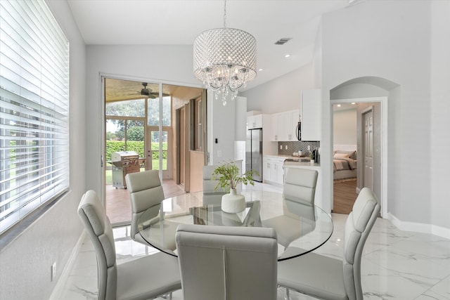 dining area with ceiling fan with notable chandelier and vaulted ceiling