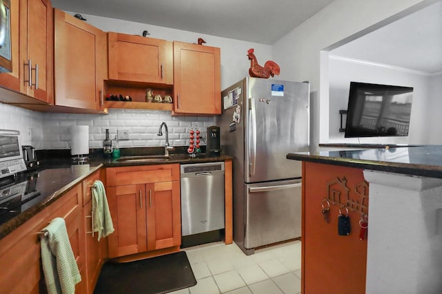 kitchen featuring appliances with stainless steel finishes, tasteful backsplash, sink, light tile patterned floors, and dark stone countertops