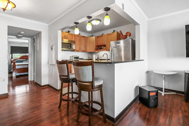 kitchen with a kitchen bar, decorative backsplash, stainless steel appliances, dark wood-type flooring, and pendant lighting