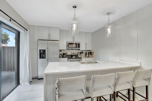 kitchen featuring white cabinetry, kitchen peninsula, pendant lighting, a kitchen bar, and appliances with stainless steel finishes