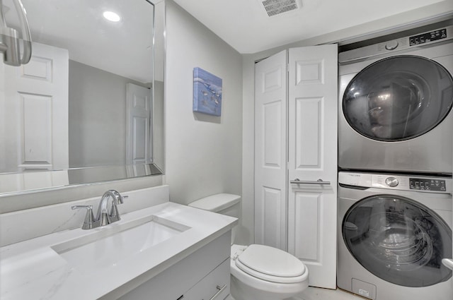 bathroom with vanity, stacked washer and clothes dryer, and toilet