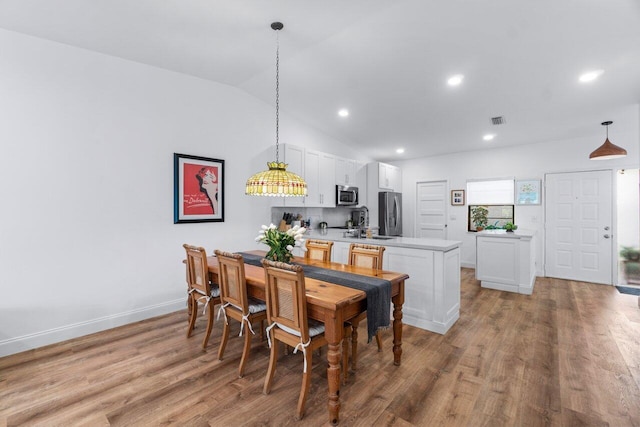 dining area with light wood-type flooring and vaulted ceiling