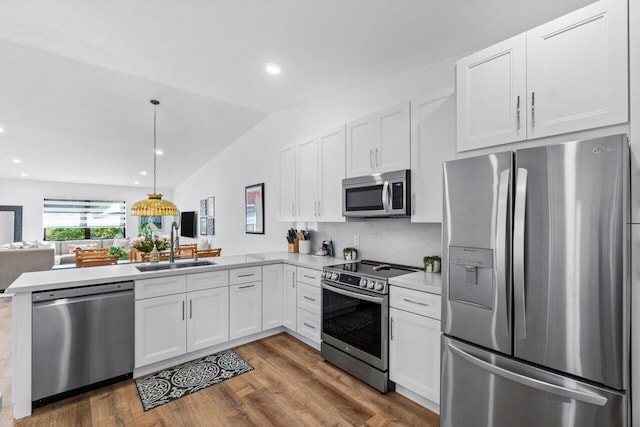 kitchen featuring sink, kitchen peninsula, hanging light fixtures, white cabinetry, and stainless steel appliances