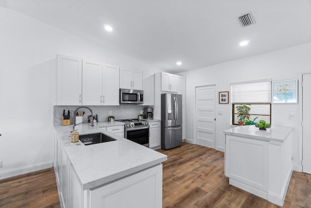 kitchen featuring white cabinetry, sink, stainless steel appliances, dark hardwood / wood-style flooring, and kitchen peninsula