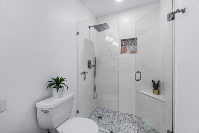 bathroom featuring toilet and a shower with door