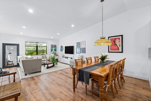 dining space featuring wood-type flooring and vaulted ceiling