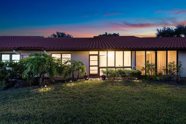 back house at dusk featuring a yard