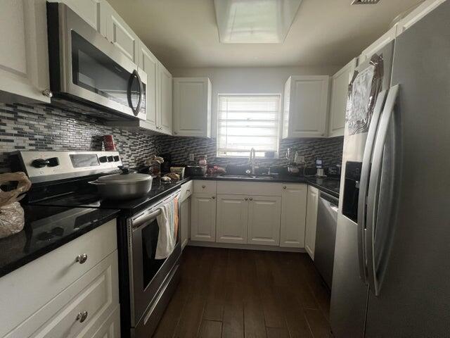 kitchen with tasteful backsplash, white cabinetry, sink, and stainless steel appliances