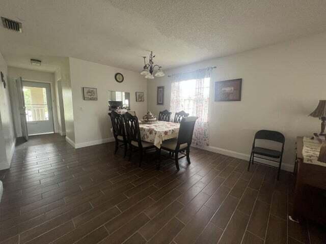 dining space with dark hardwood / wood-style flooring, a textured ceiling, and a notable chandelier