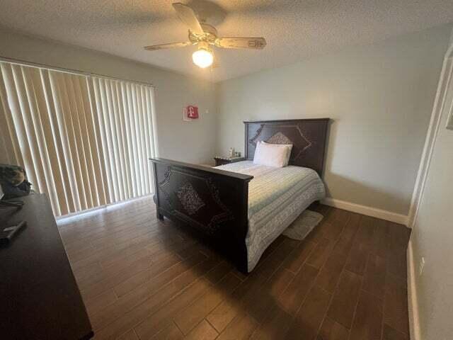 bedroom with a textured ceiling, dark hardwood / wood-style flooring, and ceiling fan