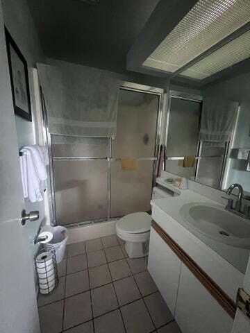 bathroom featuring tile patterned flooring, vanity, toilet, and an enclosed shower