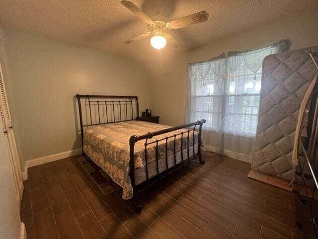 bedroom featuring a textured ceiling, ceiling fan, and dark wood-type flooring