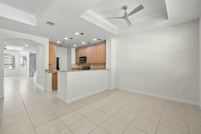 kitchen featuring ceiling fan, a raised ceiling, kitchen peninsula, and crown molding