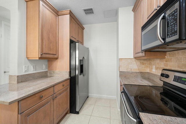 kitchen featuring light stone counters, light tile patterned floors, backsplash, and appliances with stainless steel finishes