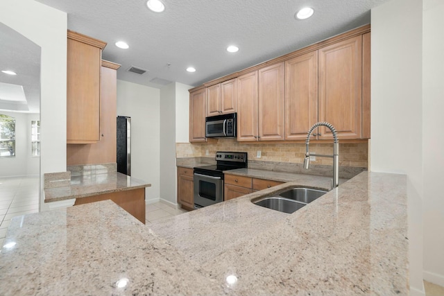 kitchen featuring sink, light brown cabinets, light stone counters, light tile patterned floors, and appliances with stainless steel finishes