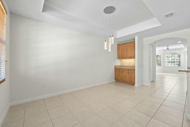 empty room featuring ceiling fan, light tile patterned flooring, a textured ceiling, and a tray ceiling