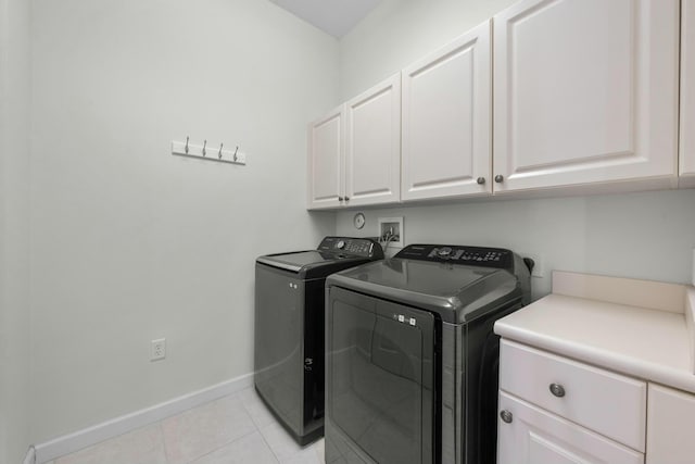 washroom with washer and clothes dryer, light tile patterned floors, and cabinets