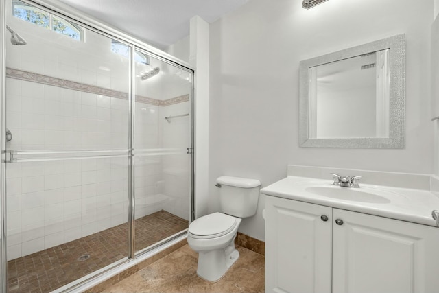 bathroom with tile patterned floors, vanity, a shower with shower door, and toilet