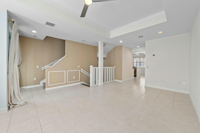 tiled empty room featuring a raised ceiling, crown molding, and ceiling fan