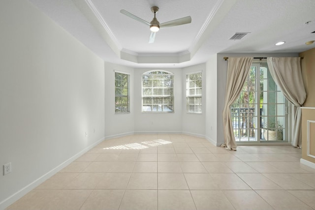 tiled empty room featuring a tray ceiling, ceiling fan, a textured ceiling, and ornamental molding