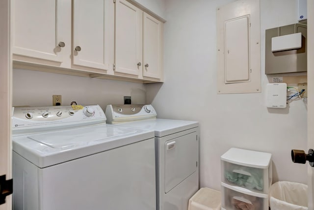 clothes washing area featuring electric panel, cabinets, and separate washer and dryer