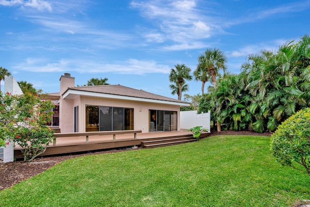 back of house with a wooden deck and a lawn