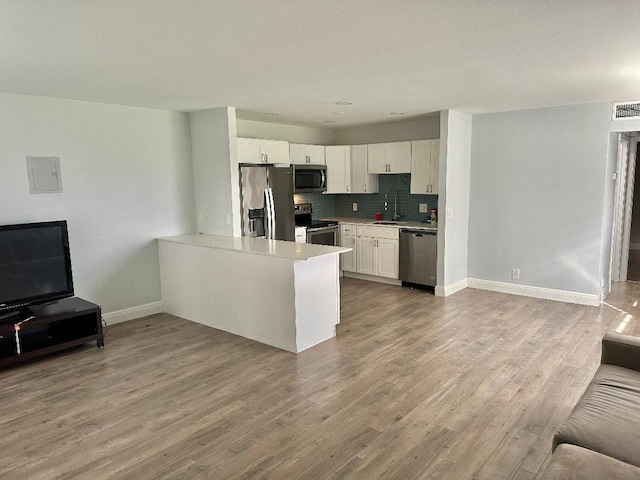 kitchen with white cabinetry, sink, kitchen peninsula, stainless steel appliances, and light wood-type flooring