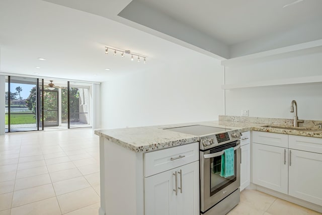 kitchen with floor to ceiling windows, stainless steel electric stove, white cabinets, sink, and light stone counters