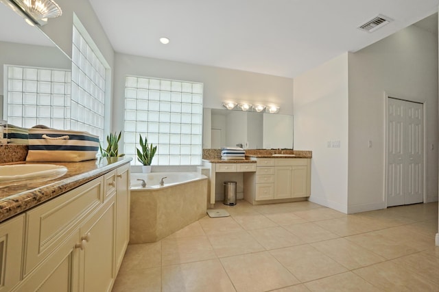 bathroom with tile patterned flooring, vanity, and tiled tub